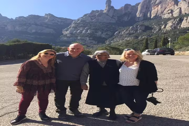 Tourists enjoying Montserrat's scenic backdrop while exploring the historic site in beautiful weather.