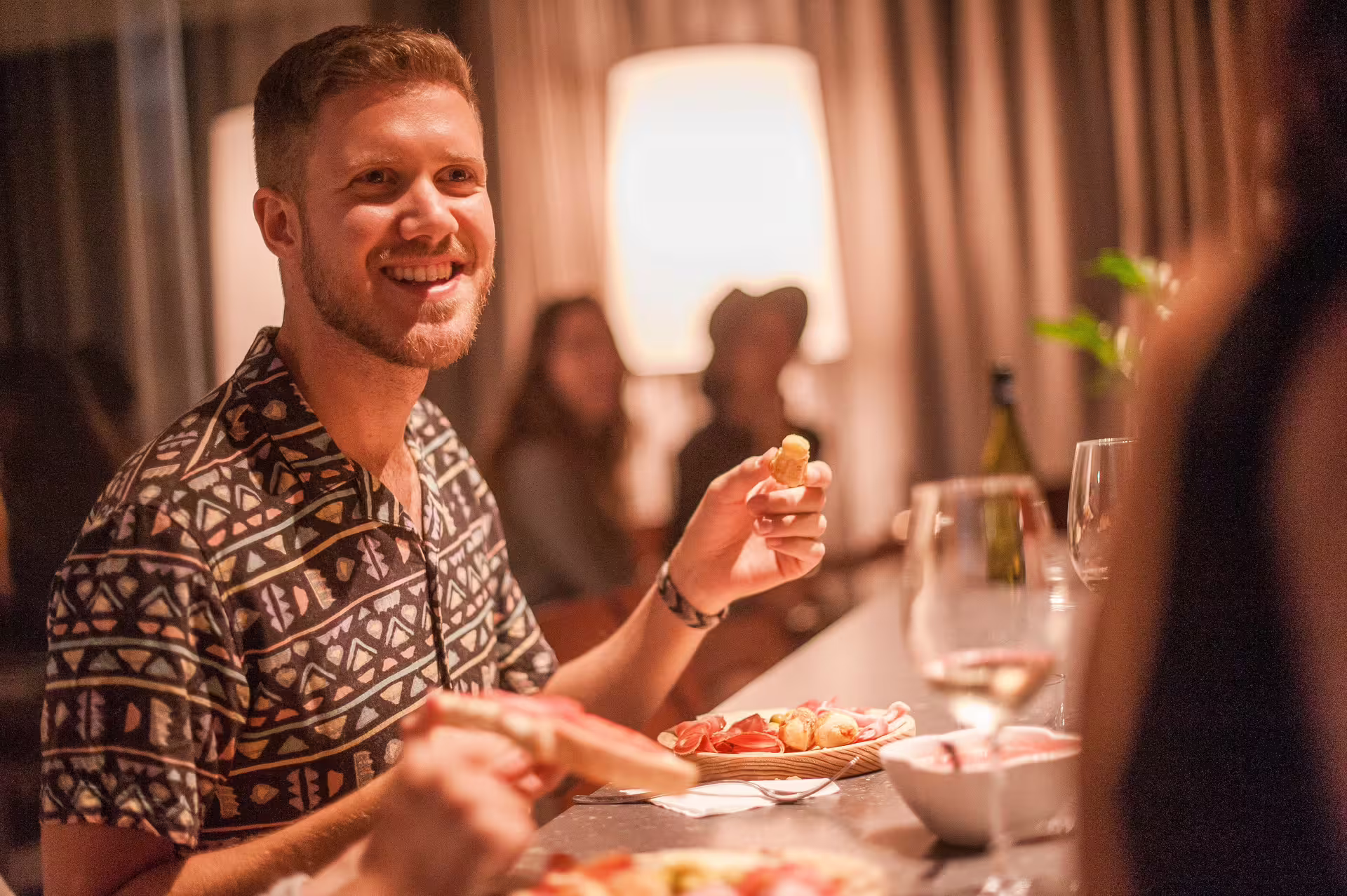 A man enjoys a tapas and wine experience in Montserrat, seated at a cozy bar with a warm atmosphere and friendly ambiance.