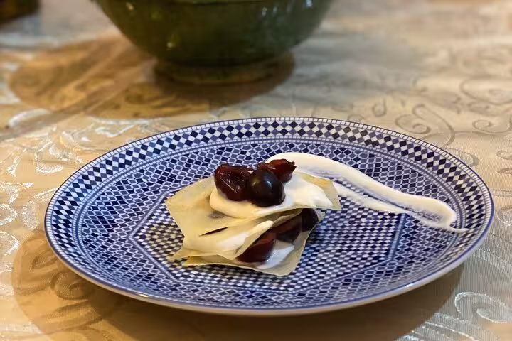 Delicious Moroccan dessert with cherries and cream on a patterned blue plate, featured in Yassine's cooking class.