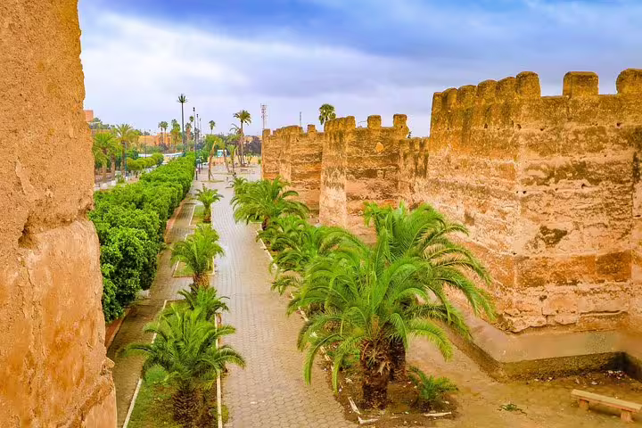 Palm-lined walkway beside ancient kasbah walls in Morocco, stop on 8-day Anti-Atlas Sahara tour