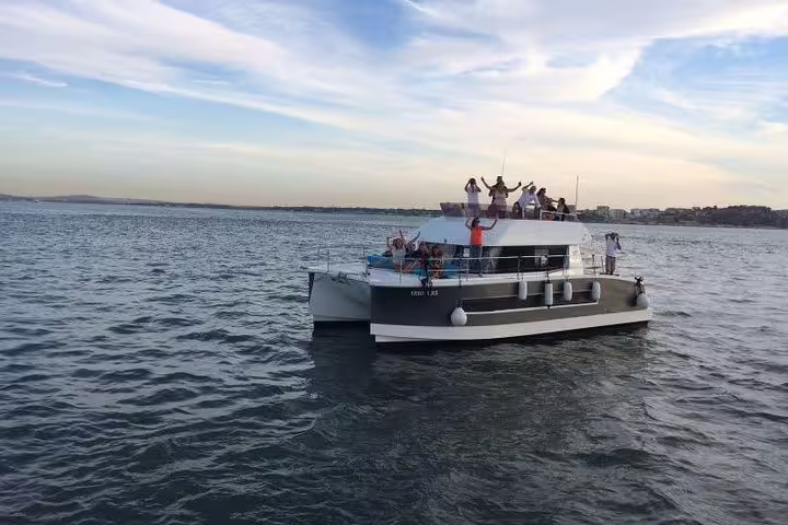 Motor catamaran in Lisbon with happy passengers enjoying a scenic river cruise for up to 18 people.
