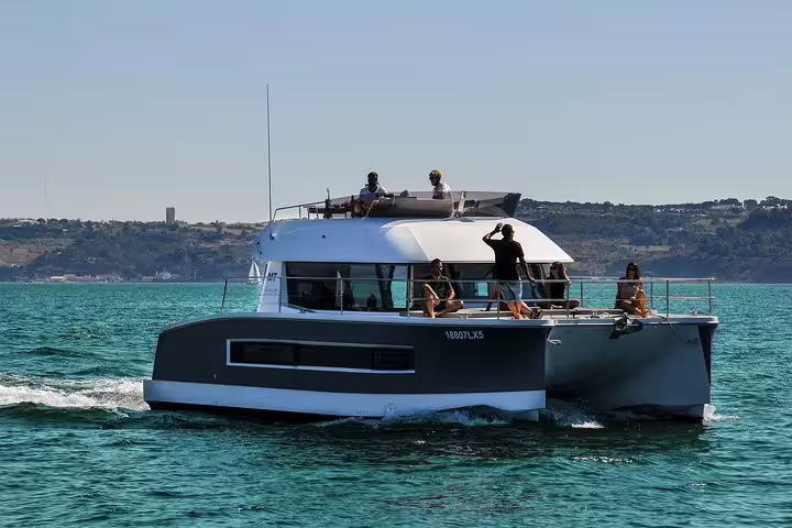 Luxurious motor catamaran sailing in Lisbon, offering a relaxing tour for up to 18 people under clear skies.