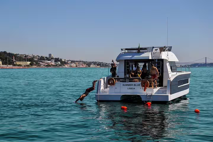 Motor catamaran in Lisbon with people diving into the ocean, offering a thrilling maritime adventure for up to 18 guests.