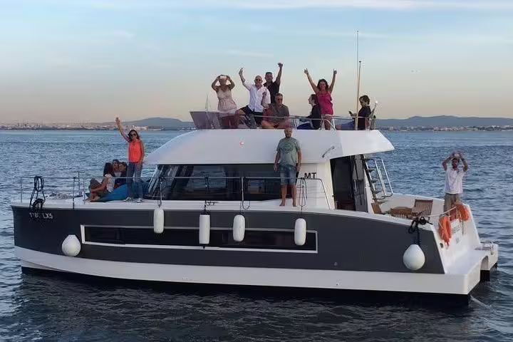 Group of people enjoying a sunset cruise on a spacious motor catamaran in Lisbon, ideal for private parties and scenic tours.