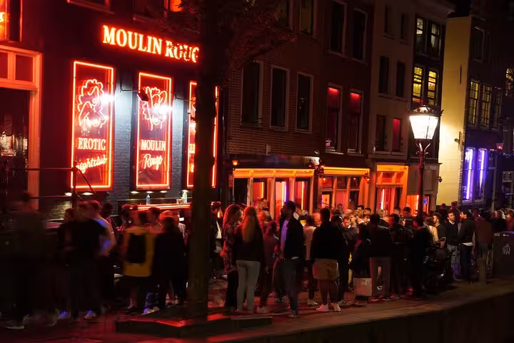 Crowds outside Moulin Rouge neon windows in Amsterdam Red Light District on a private guided night tour