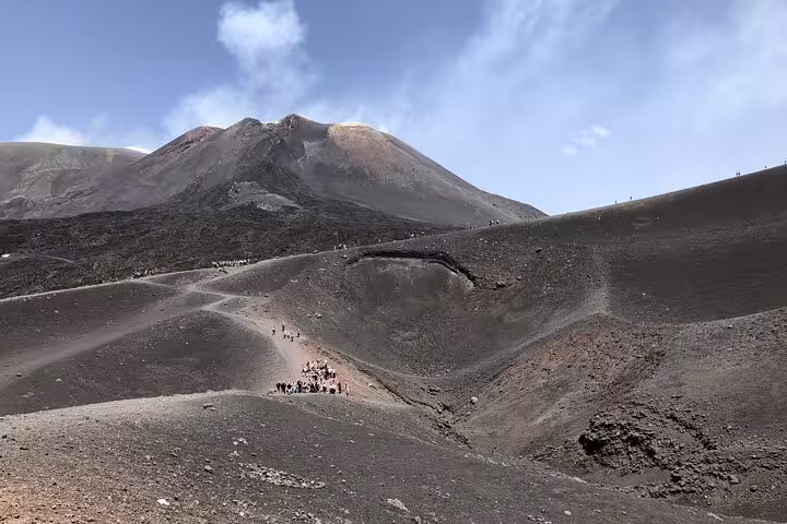 Tourists explore the rugged volcanic landscape of Mount Etna during a half-day guided tour at 3000 meters.