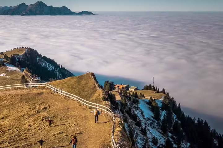 Scenic view from Mount Rigi summit overlooking a sea of clouds and alpine landscape with visitors exploring.