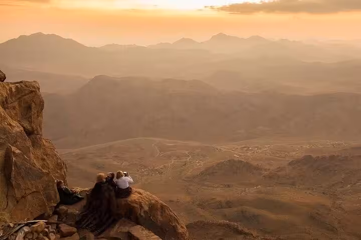 Hikers resting on Mount Sinai summit at dawn during St Catherine’s Monastery excursion from Sharm