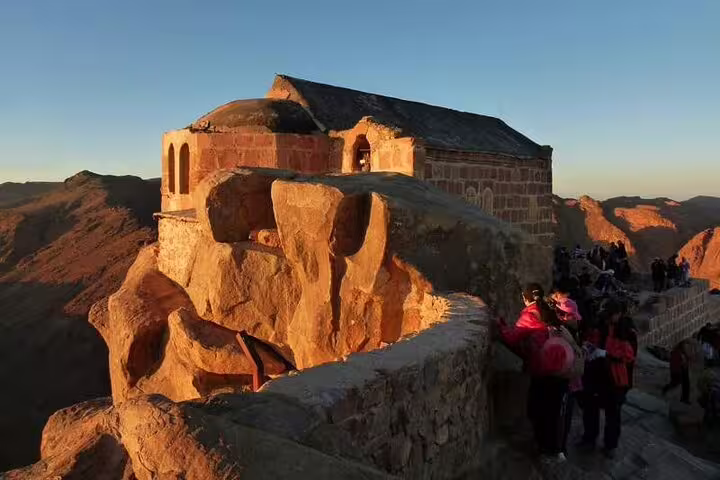 Sunrise at Mount Sinai summit chapel with hikers on the trail, Mount Sinai climb tour from Dahab