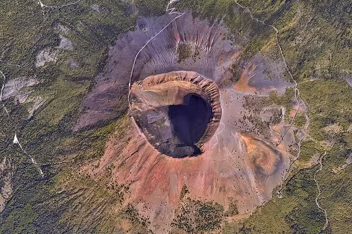 Aerial view of Mount Vesuvius' crater, highlighting the stunning geological features and lush surroundings on a Sorrento tour.