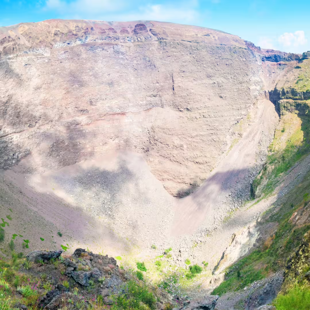 Sunlit interior of Mount Vesuvius volcanic crater with rocky slopes seen on escorted day tour plus local wine tasting