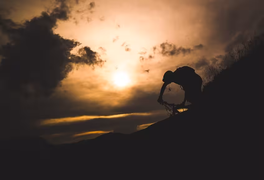 Silhouette de VTT au coucher du soleil, expérience aventure pour rouler sur la neige en montagne