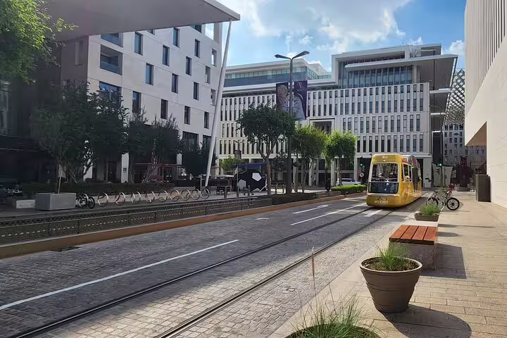 Modern tram passing through the vibrant streets of Msheireb Downtown Doha, showcasing contemporary architecture and urban culture.