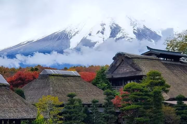 Scenic view of Mt. Fuji with traditional thatched roofs and vibrant autumn foliage on a customizable Hakone tour.
