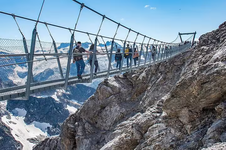 Tourists crossing the thrilling Mt. Titlis suspension bridge with breathtaking alpine views, a must-visit adventure spot.