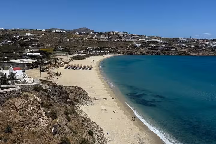 Panoramic view of a Mykonos beach bay with turquoise water and sunbeds, ideal stop on a private island tour
