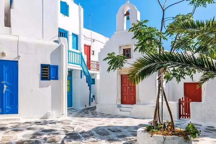 Charming Mykonos Town alley with whitewashed walls, blue shutters and chapel, private day trip from Athens