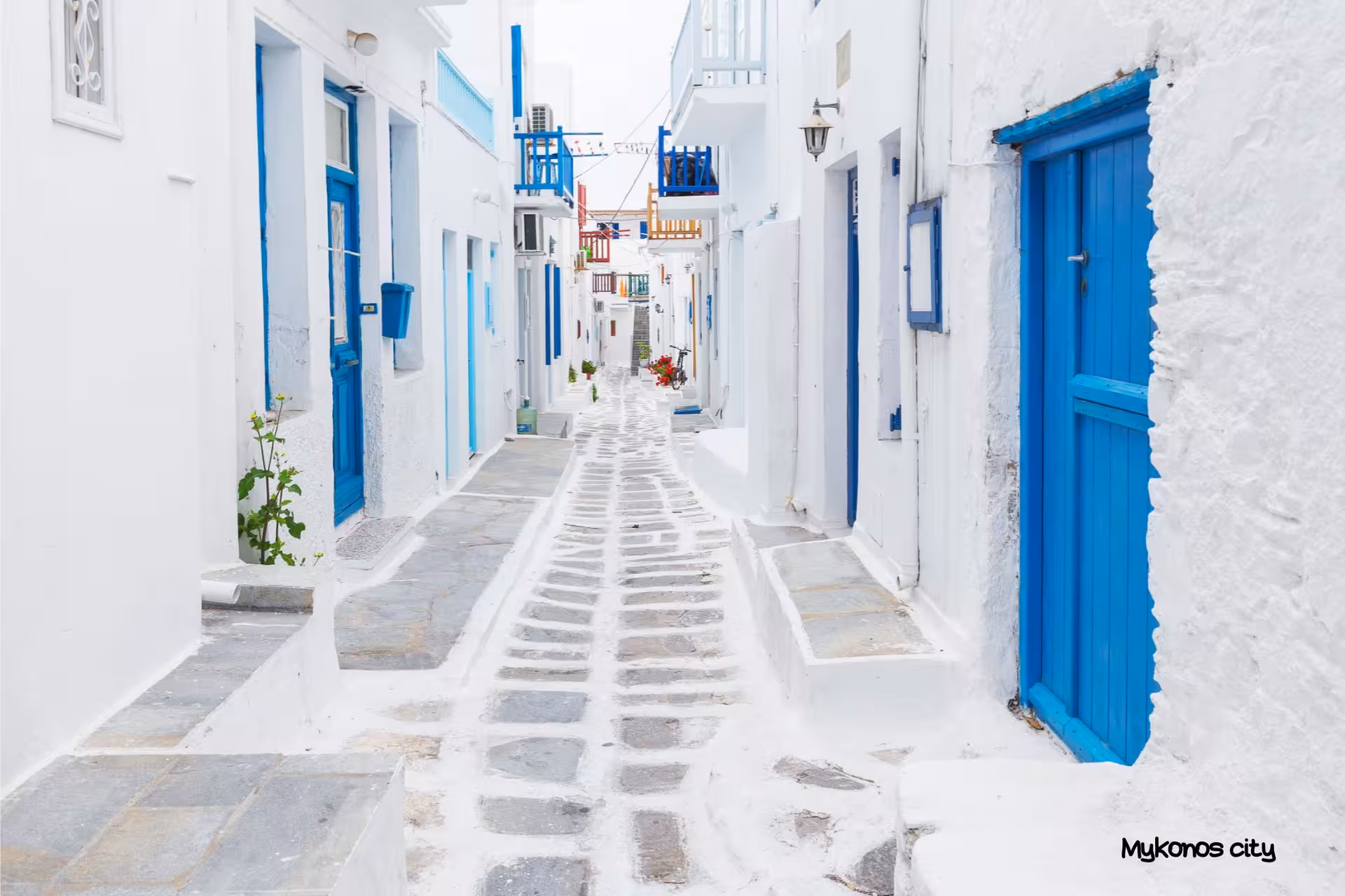 Whitewashed alley with blue doors in Mykonos Town, a highlight of Athens to Santorini Naxos Mykonos island hopping