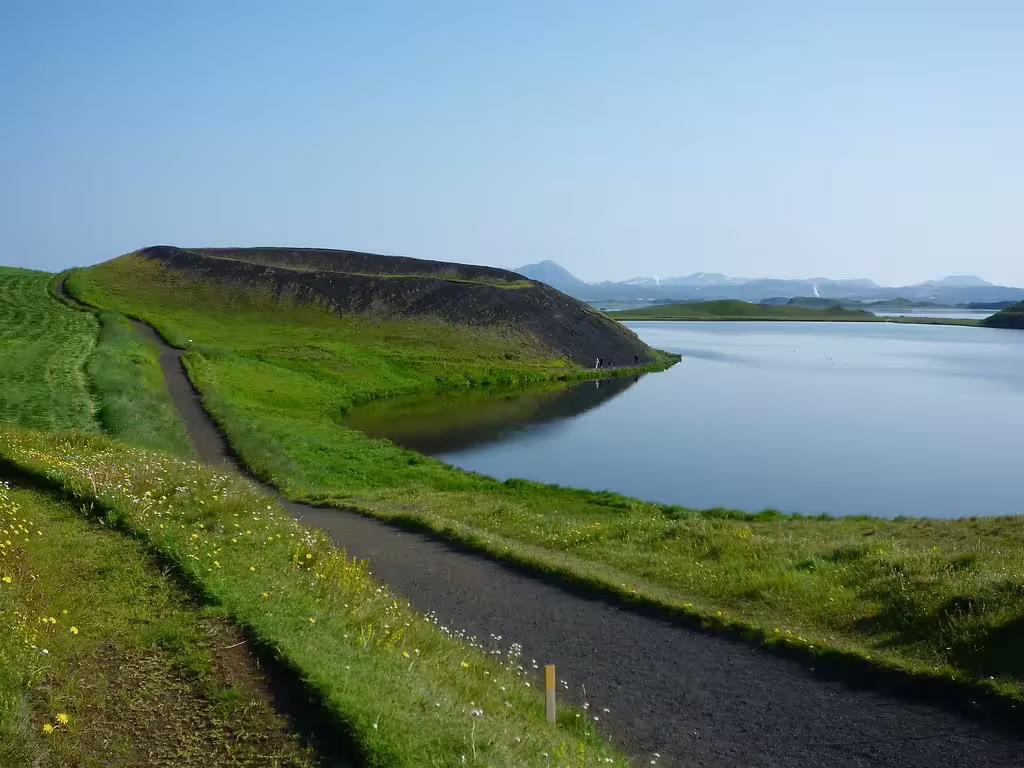 Scenic path along Lake Mývatn with volcanic pseudo-craters and calm reflective water near Akureyri, Iceland