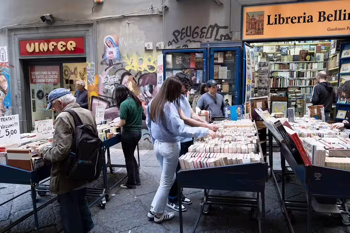 Visitors browse outdoor book stalls at Libreria Bellini in historic Naples, Italy during a guided city walking and culture tour