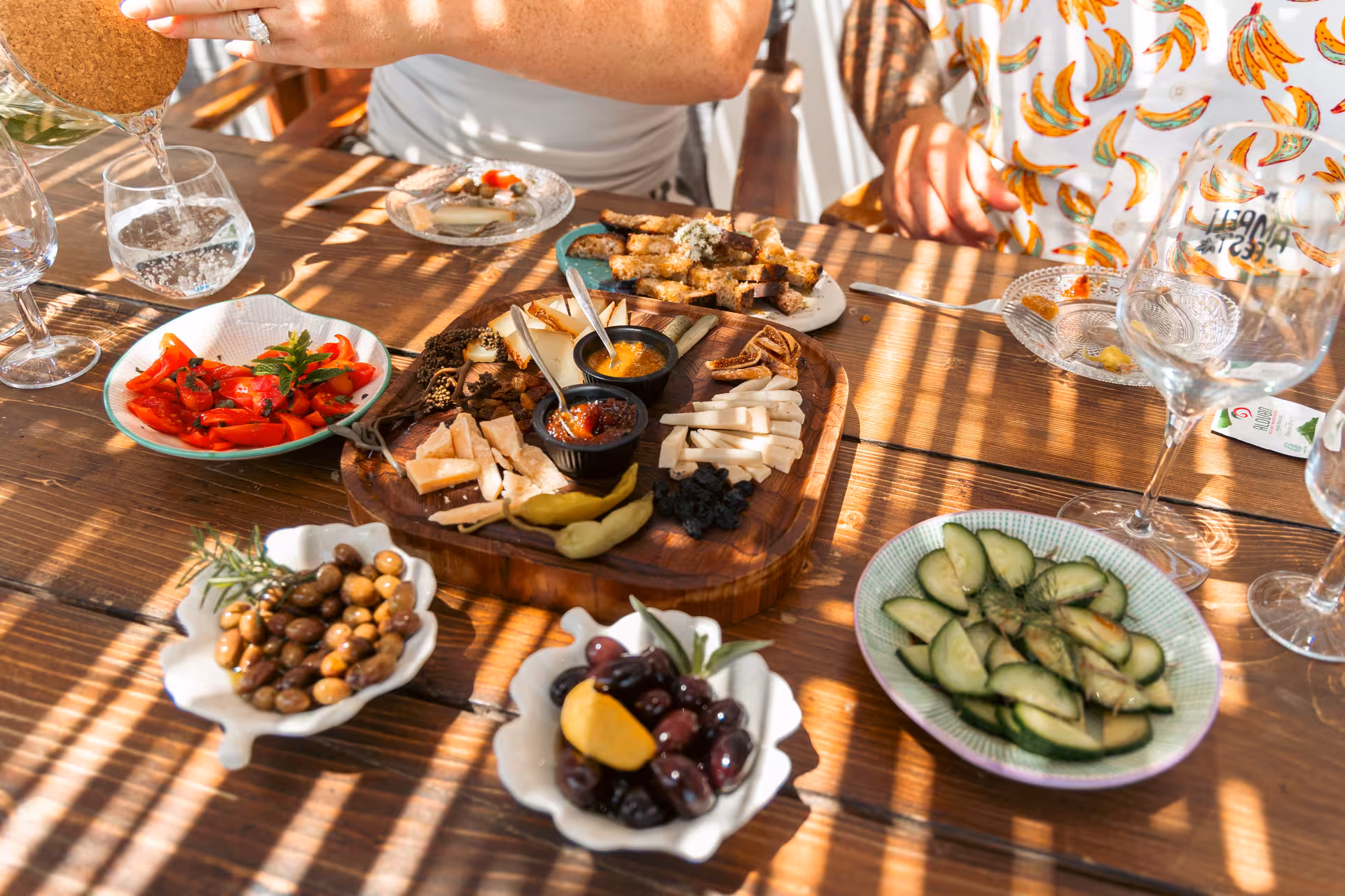 Naxos cheese and wine tasting table with local cheeses, olives, tomato salad and meze on a sunny terrace