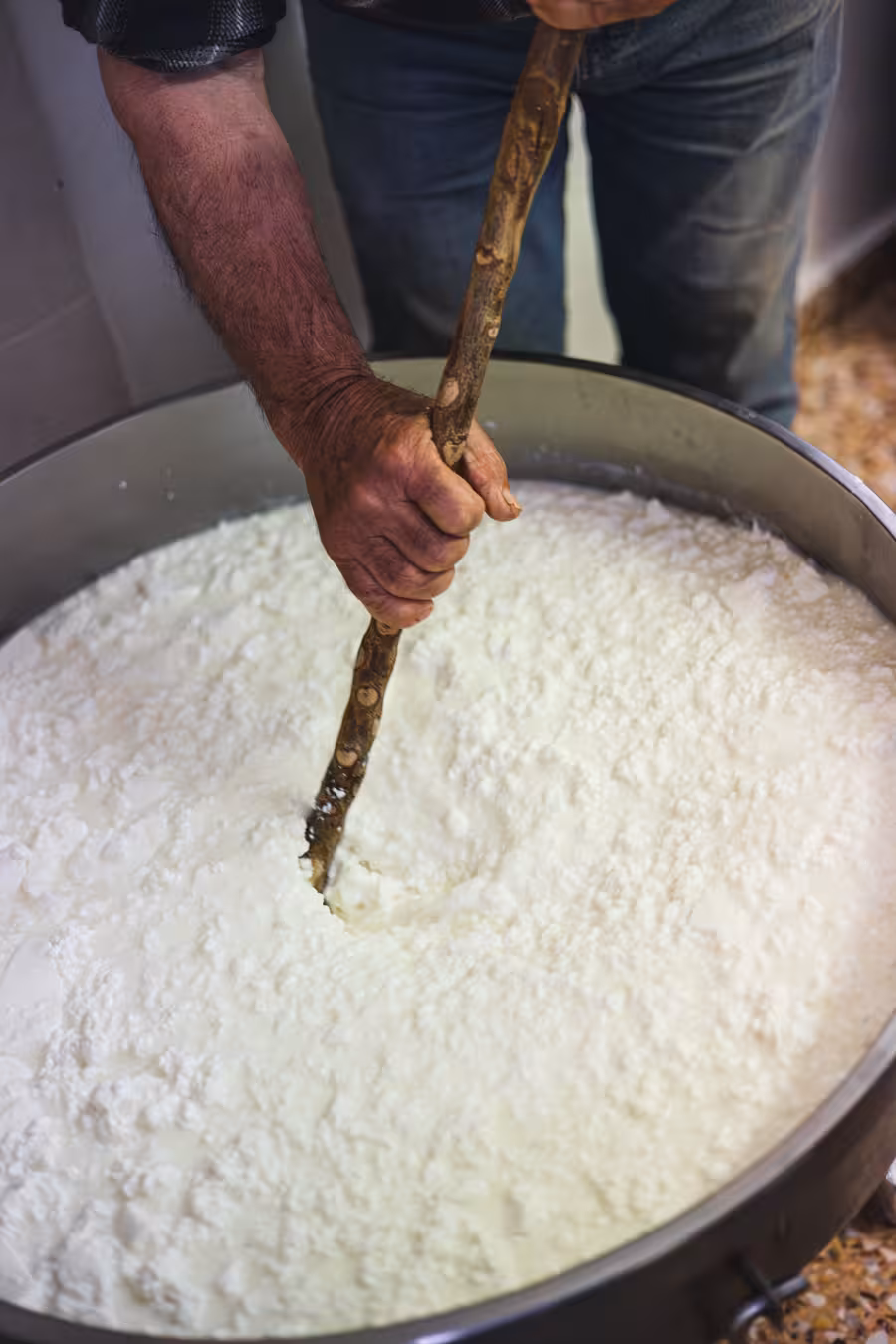 Cheesemaker stirring fresh curds in a vat during Naxos cheese and wine trails farm-to-table tasting experience