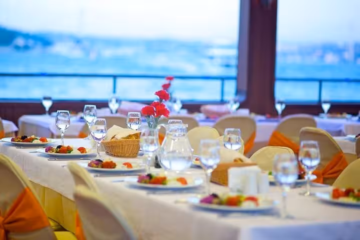 Elegant dinner tables set by the window on New Year's Eve Bosphorus cruise Istanbul, gourmet meal and views