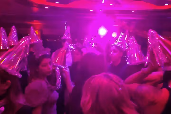 Guests in party hats dancing under neon lights on New Year’s Eve party cruise in Istanbul on the Bosphorus