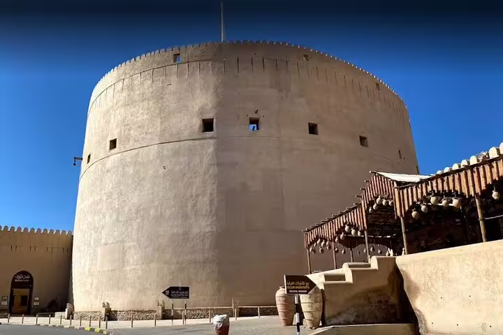 Explore the historic Nizwa Fort under a clear blue sky on the Nizwa-Al Hamra Old Village-Misfah Al Abryeen Full Day Tour.