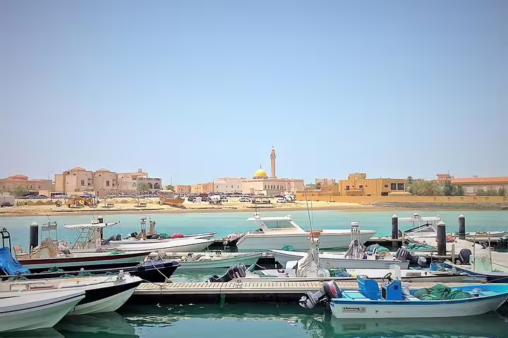 Scenic view of a marina with boats and historic architecture in North Qatar's coastal heritage site.