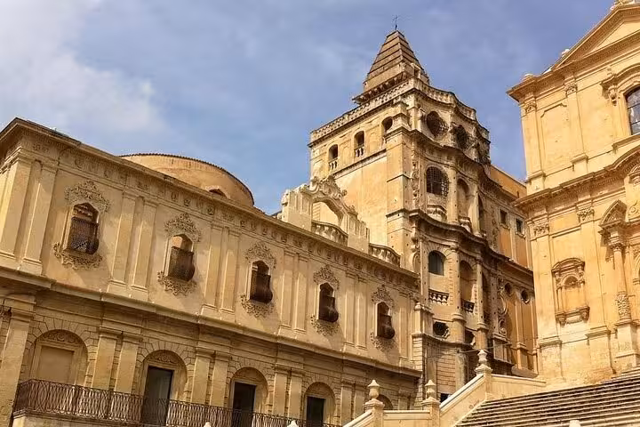 Noto's ornate Baroque cathedral facade basking in sunlight, showcasing intricate architectural details and grandeur.