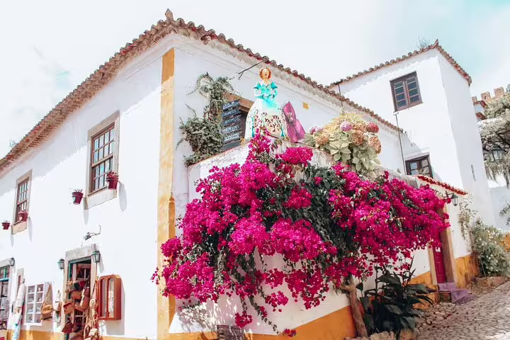 Charming corner in Óbidos with vibrant bougainvillea and traditional architecture, perfect for a Portugal tour.