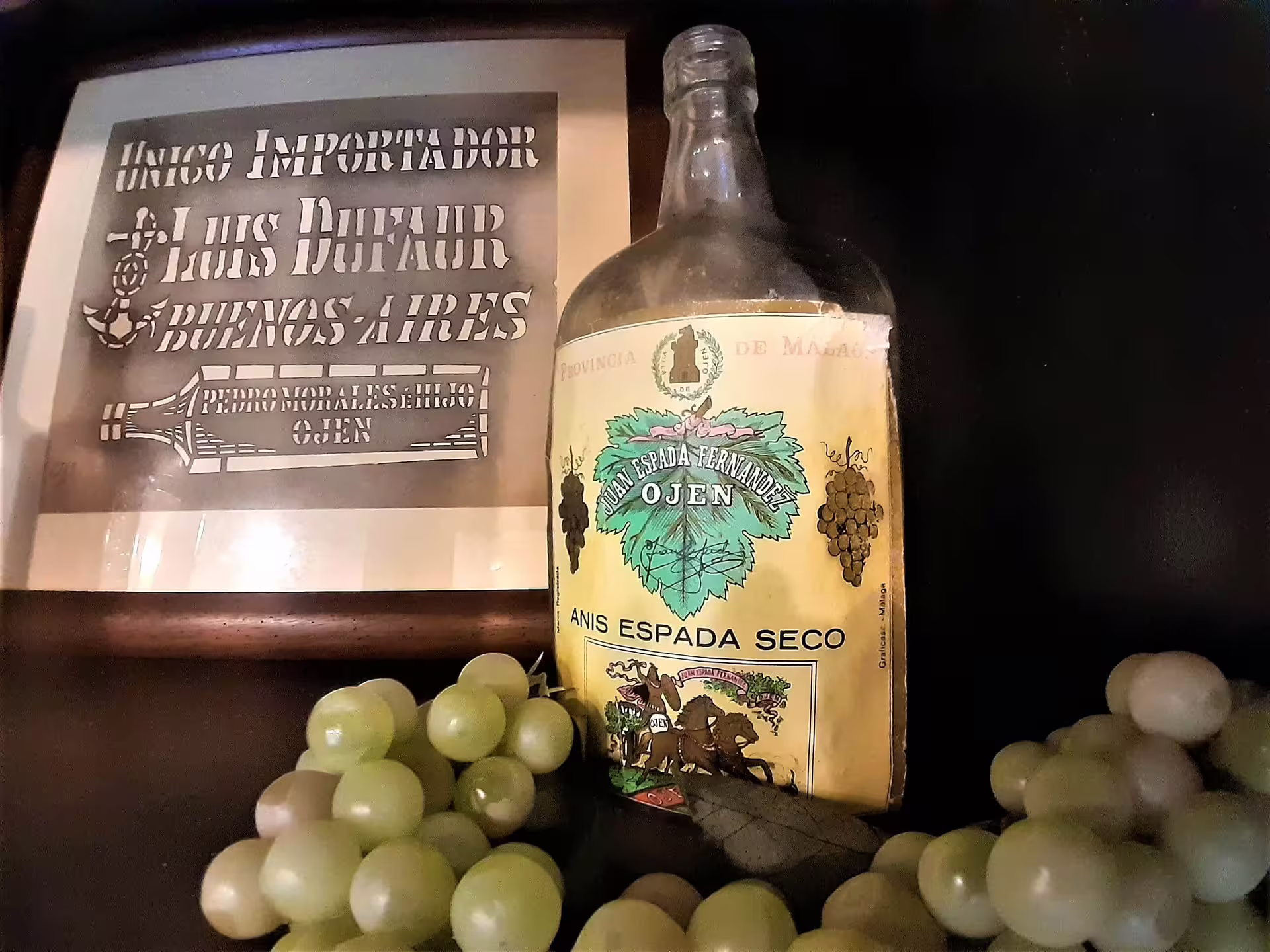 Vintage Ojen anise liqueur bottle with grapes on display, local tasting theme on an Ojen private walking tour