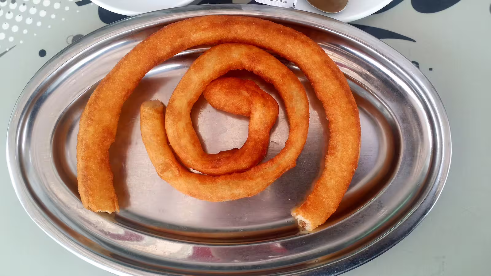 Traditional Andalusian churros spiral served on a metal tray, a tasty stop on an Ojen private walking tour