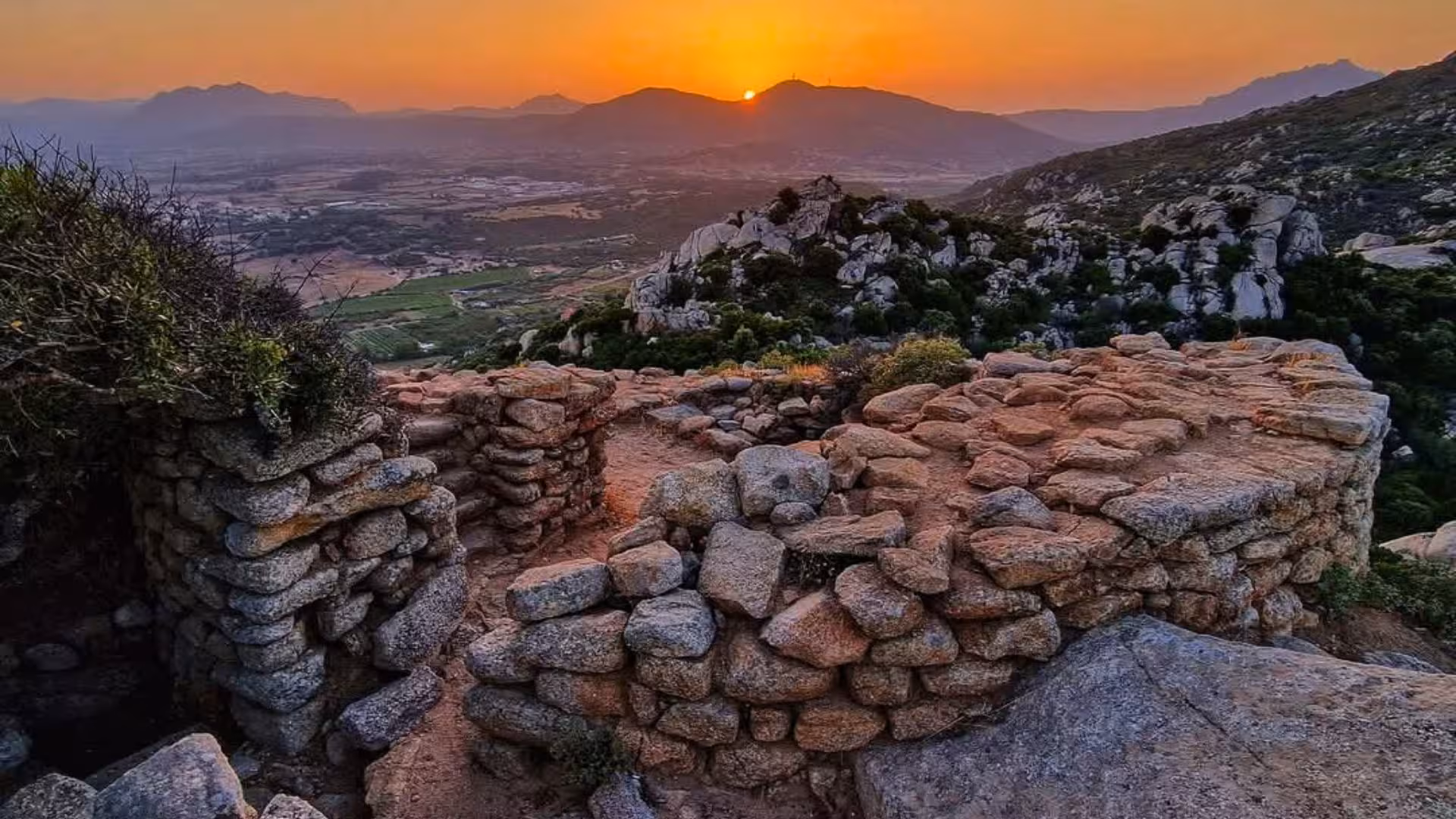 Ancient stone ruins at sunset overlooking the scenic landscape of Olbia, highlighting historical and archaeological beauty.