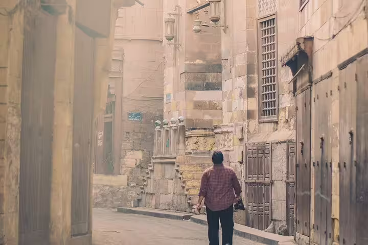Traveler walking a quiet Old Cairo alley, exploring Islamic and Christian Cairo on a guided day tour, Egypt