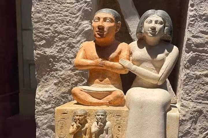 Old Kingdom limestone couple statue in museum, must-see on VIP Giza Pyramids tour and Grand Egyptian Museum visit