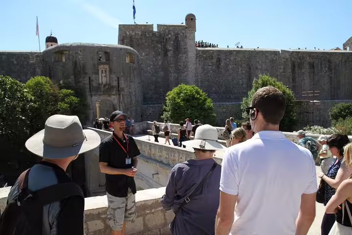 Old Town walking tour guide briefing travelers on a viewpoint with medieval city walls in the background