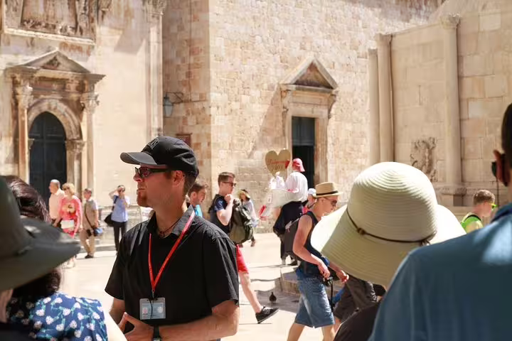 Local guide leads Discover the Old Town Walking Tour past historic stone cathedral in sunny square