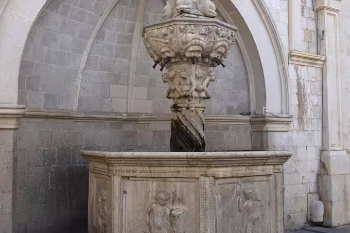 Historic stone fountain and carved basin in Old Town courtyard on a private guided walking tour