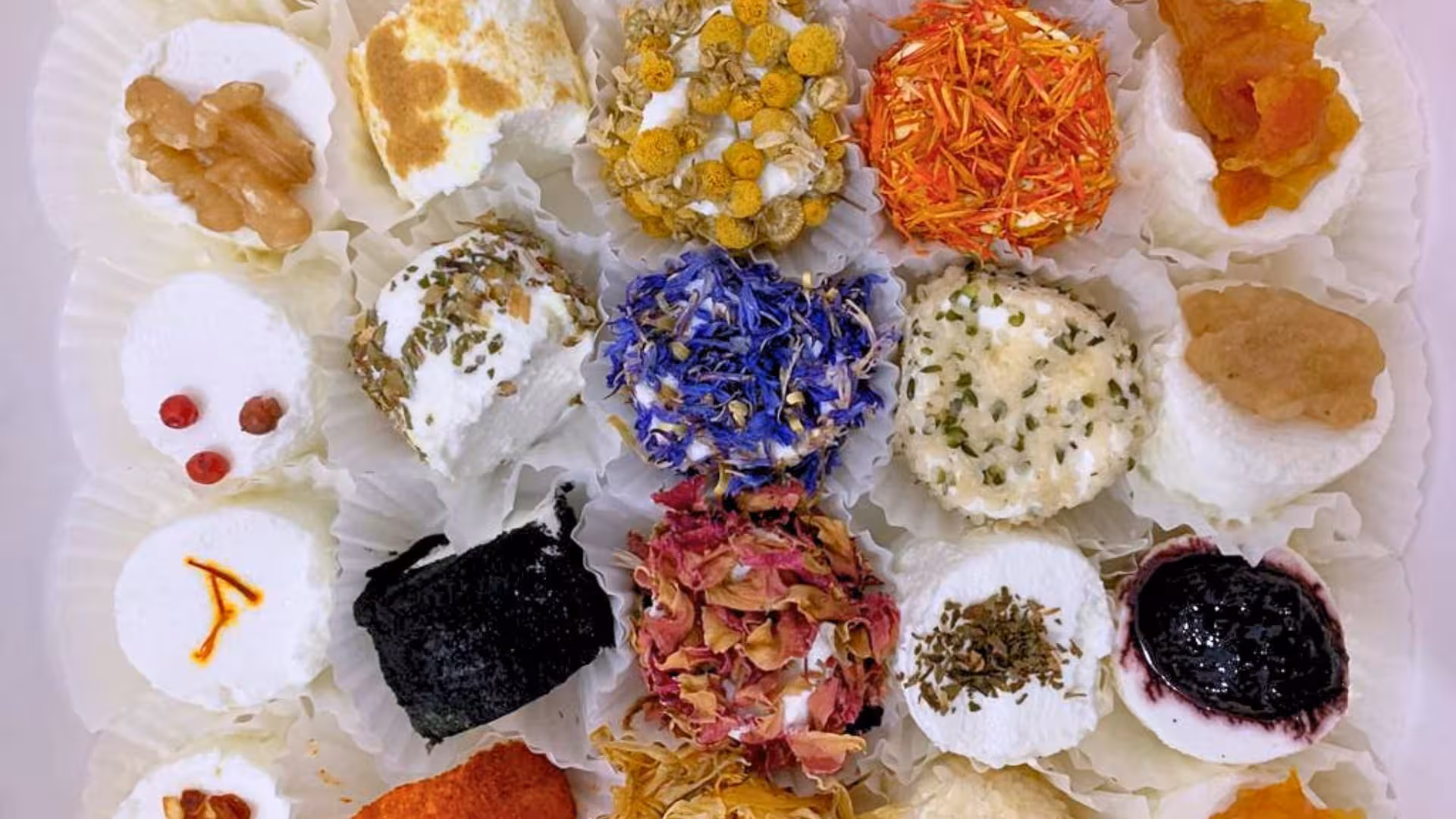 Assorted artisan goat cheeses with colorful toppings, ideal for Oliena cheese tasting experience.
