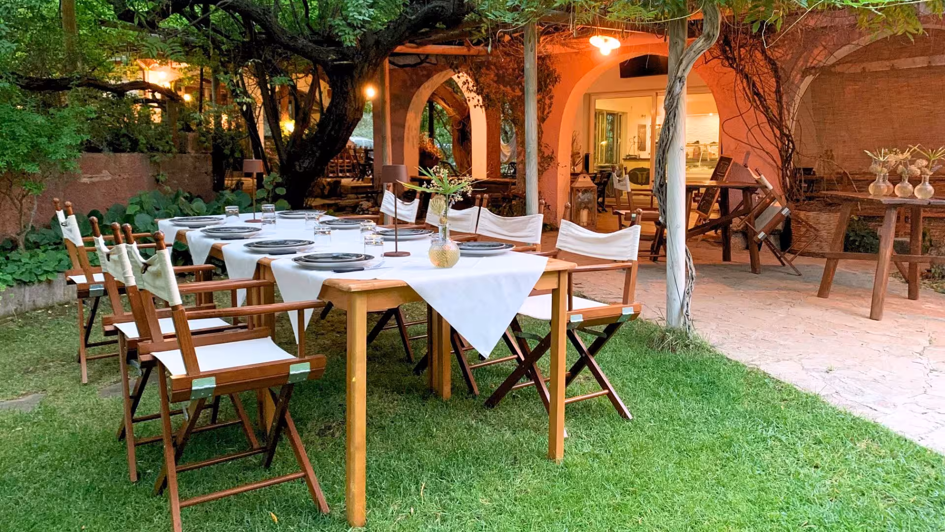 Outdoor dining setup with elegant table setting, ideal for enjoying local goat cheese in Oliena's serene garden.