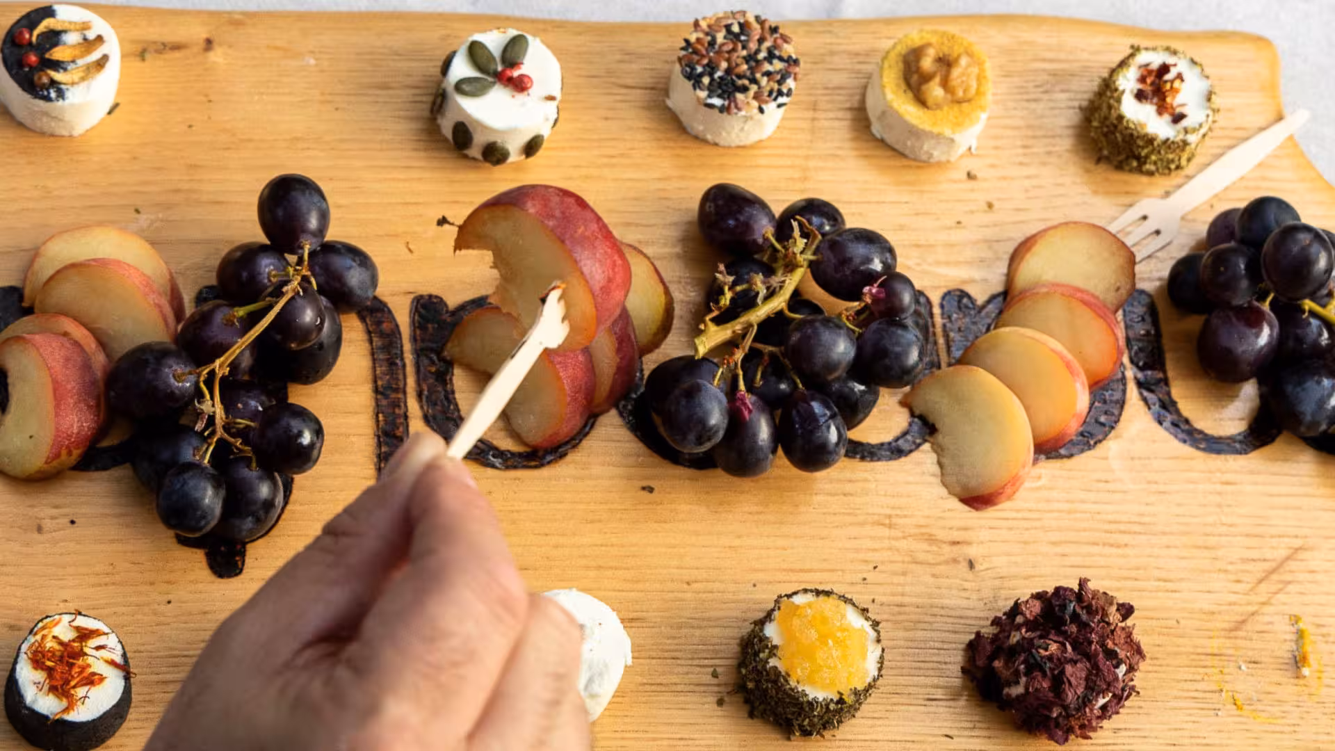 Artisan cheese platter with grapes and apple slices, perfect for Oliena goat cheese tasting tour.