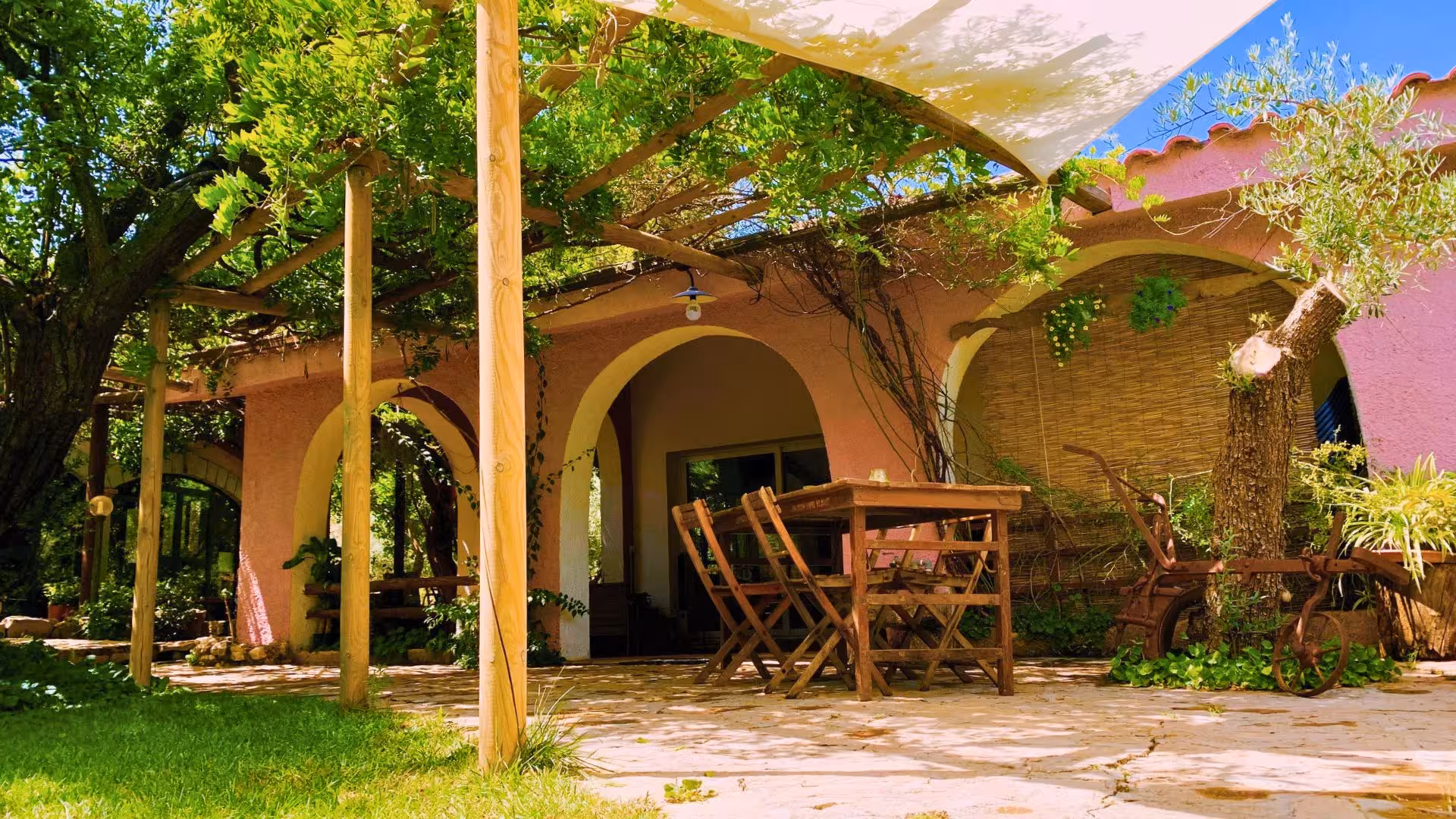 Charming shaded terrace with rustic wooden seating for an authentic Oliena goat cheese tasting experience.