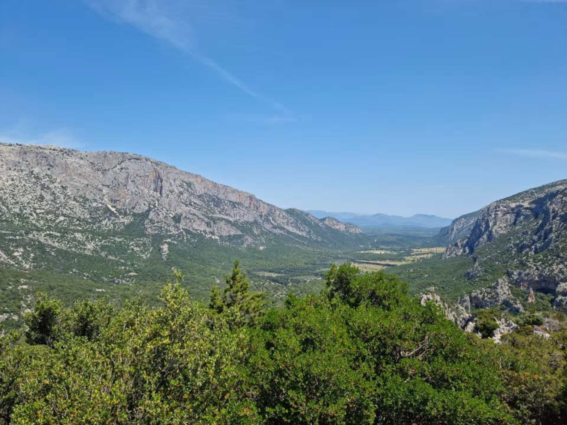Breathtaking panoramic view of lush valleys and rugged mountains on the Oliena to Mount Tiscali trekking route.