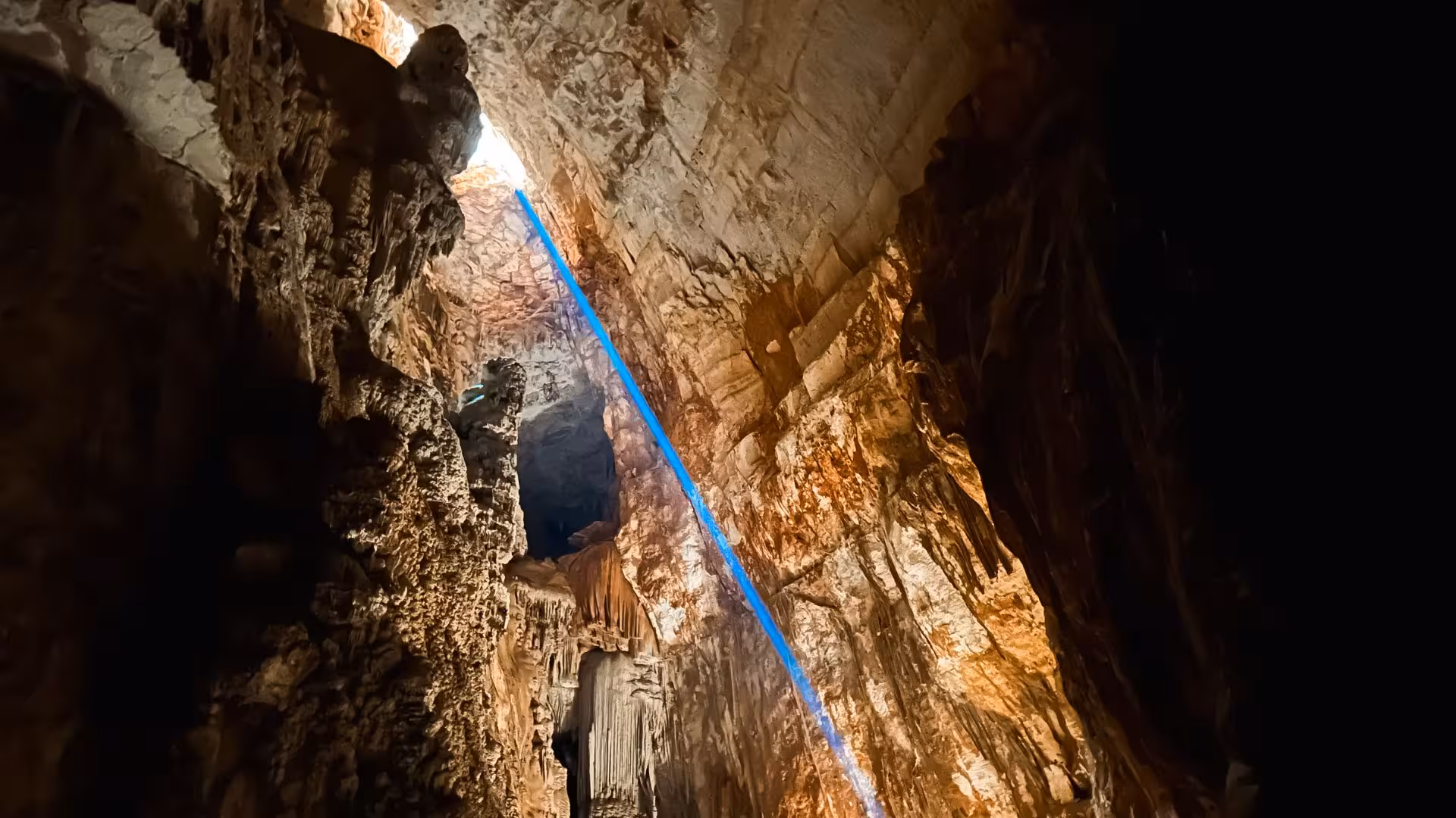 Sunlight beams into Sa Nurre de Su Hoda cave, highlighting its stunning stalactites, a highlight of Oliena trekking tours.