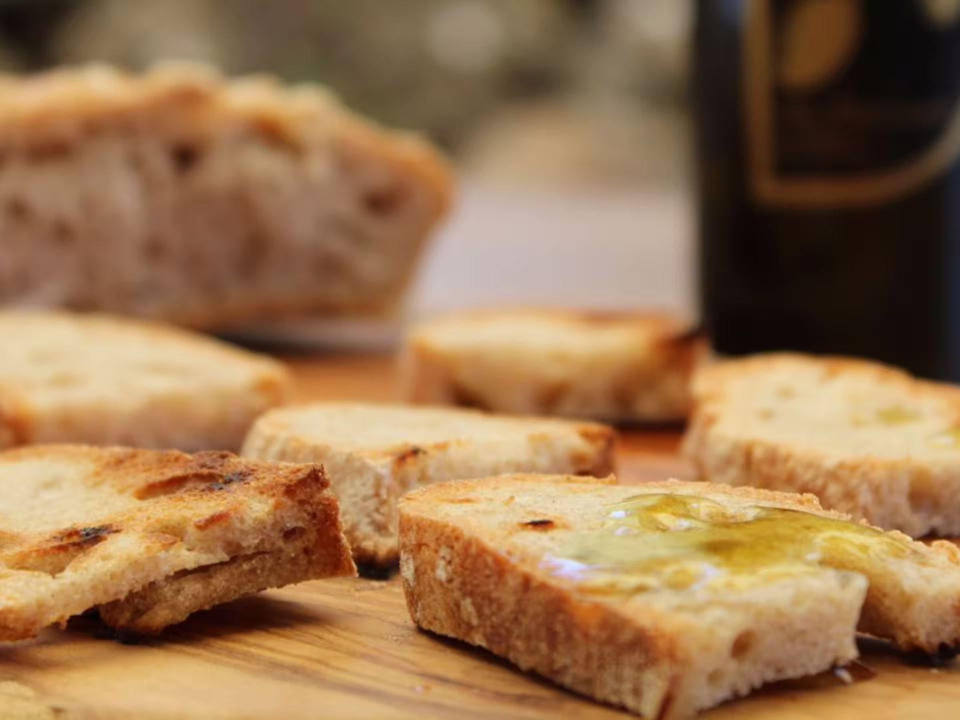 Slices of fresh bread drizzled with premium olive oil during a tasting session at a Pisa olive mill.
