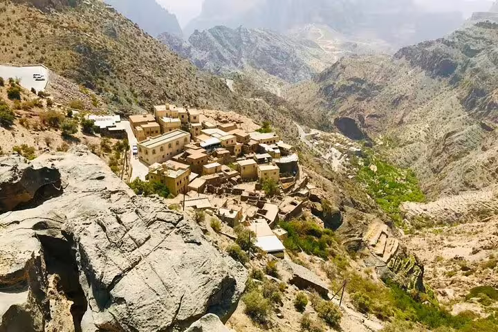 Scenic view of a traditional Omani village nestled in the rugged mountains, featured in the Oman package tour.