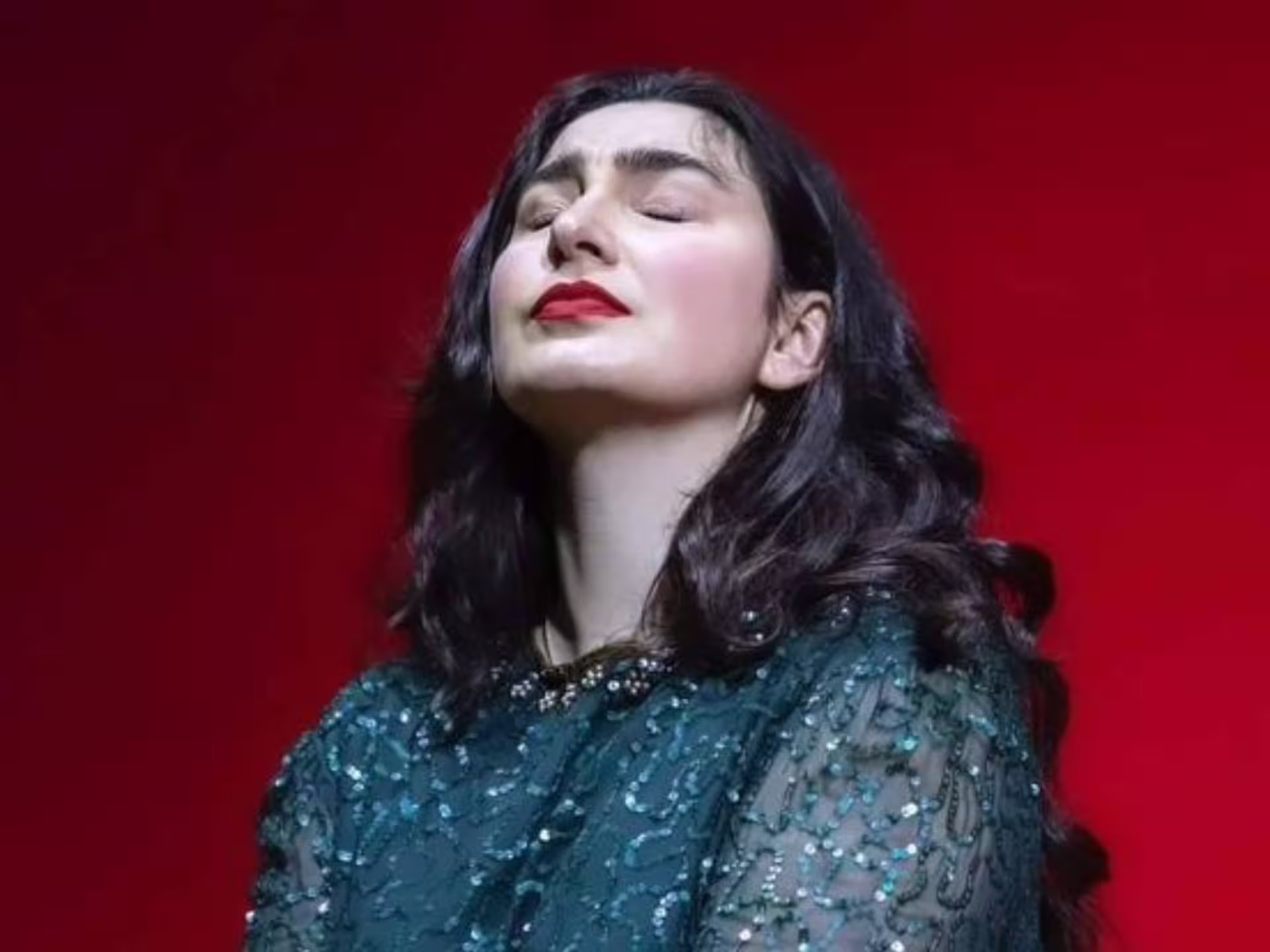 Opera singer in an elegant dress performing passionately against a vibrant red background in Verona Palace.