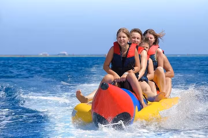 Guests riding banana boat on Hurghada Orange Bay VIP cruise, Red Sea water sports fun after snorkeling